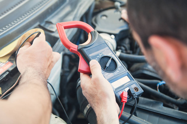 Mechanic with a multimeter testing car engine. Car service  - Photo, image