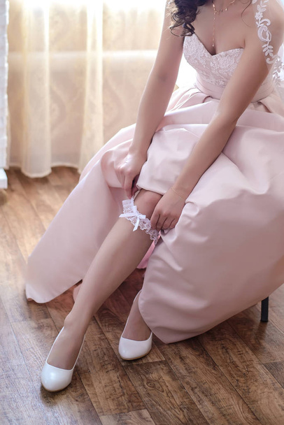 The bride wears a wedding garter on her leg - Фото, зображення