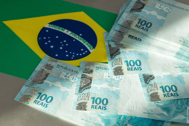Бразильські банкноти на тлі прапора країни. - Фото, зображення