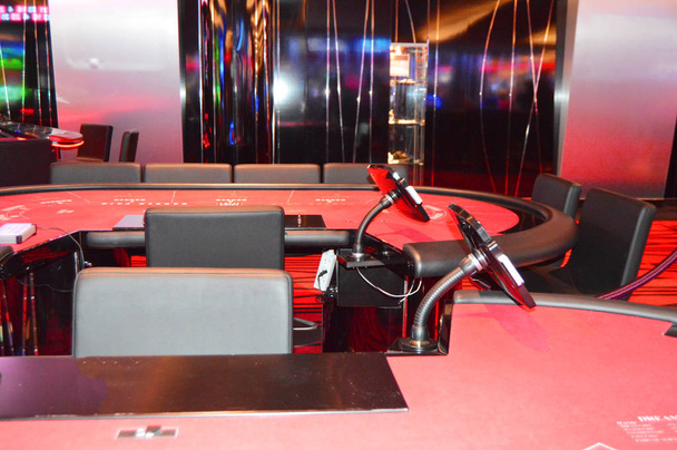 Игровой стол с красной тканью в интерьере казино
 - Фото, изображение