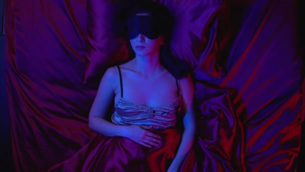Młoda kobieta śpi sama w łóżku, oczy pokryte maską, odpoczywa w nocy - Materiał filmowy, wideo