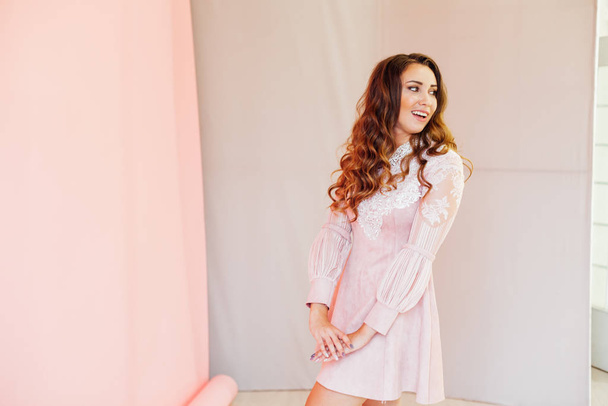 Retrato de una hermosa mujer de moda con rizos de pelo en un vestido rosa
 - Foto, imagen