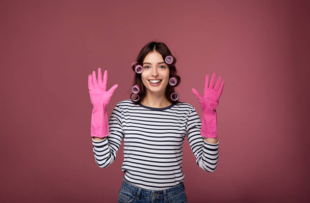 Smiling girl in curlers and rubber gloves for cleaning. - Photo, image