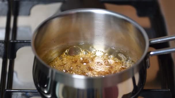 Boiling caramel syrup on stove in pot pan. - Footage, Video