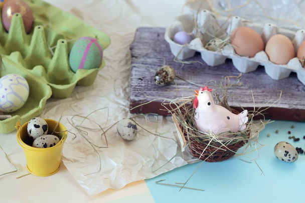 Іграшкова курка, яйця, сіно, великодній декор на світлому фоні
 - Фото, зображення