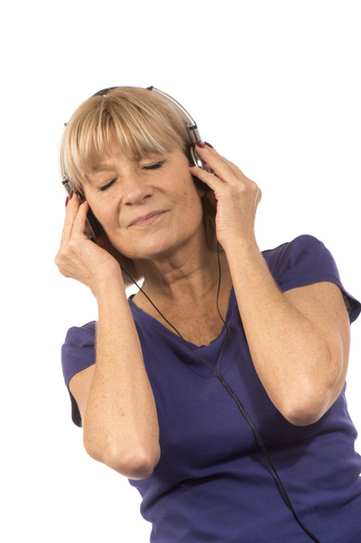 Vanhempi nainen 50-60vuotta kuunnellen musiikkia stereokuulokkeilla
 - Valokuva, kuva