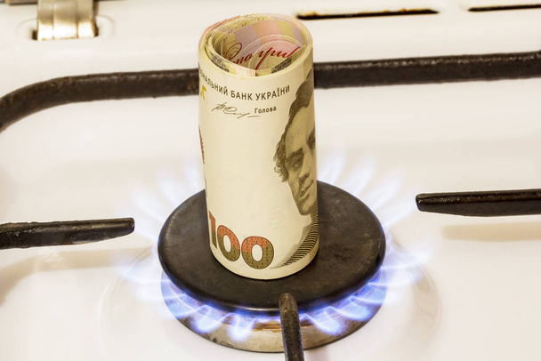 Pilha de cem notas de hryvnia em um fogão a gás no centro de conforto de gás, queimaduras a gás
. - Foto, Imagem
