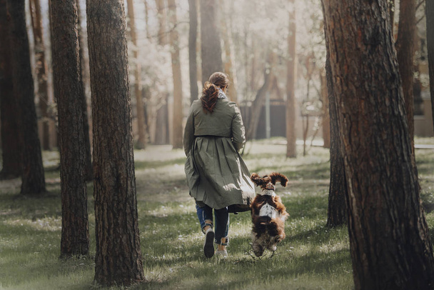young woman and dog running in the park, rear view - Foto, Imagen