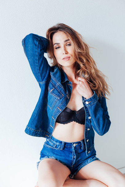 Portrait of a beautiful fashionable woman in jeans and black lingerie style - Фото, изображение