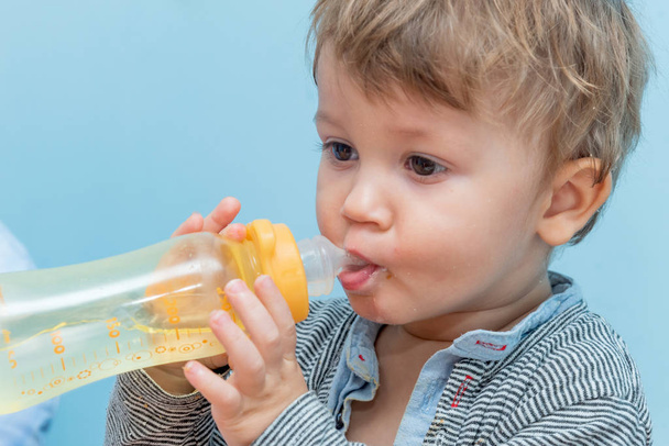 Roczny chłopiec pijący wodę z butelki dla dziecka. - Zdjęcie, obraz