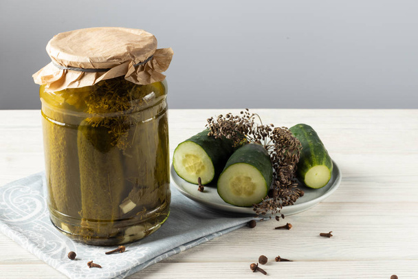 Gherkins. Pickles. Salted Cucumbers still-lifeHomemade pickled cucumbers in a glass jar on a white wooden background - Photo, image