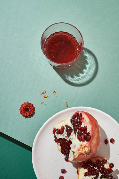 Sliced pomegranates and glasses with juice - still life on a green background - Photo, Image