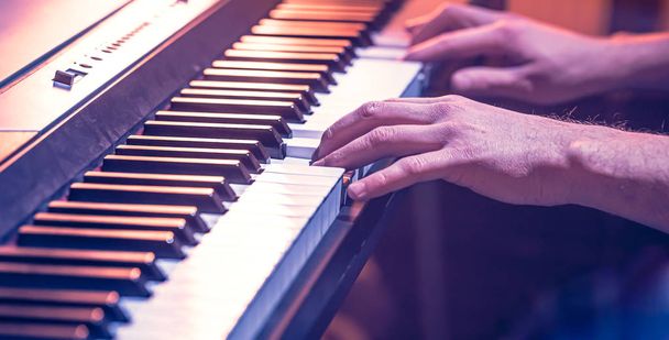 male hands on the piano keys closeup of a beautiful colorful bac - Фото, изображение