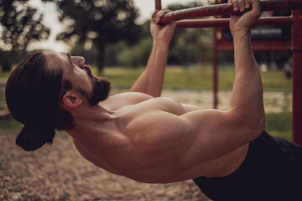 baard man doet Roemeense pull up in de outdoor gym - Foto, afbeelding