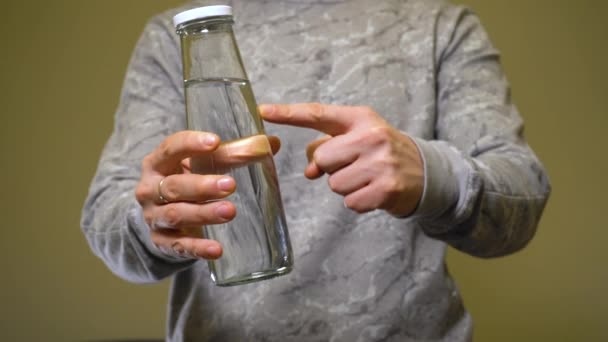 Człowiek zatwierdzający szklaną butelkę z czystą wodą. Koncepcja zerowej ilości odpadów. - Materiał filmowy, wideo