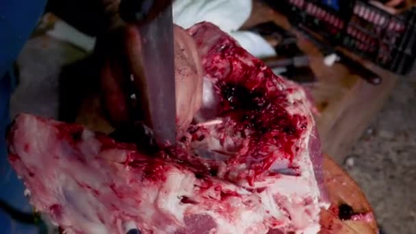 Macro vista de un trabajador cortando con un cuchillo grande la parte interna del cráneo de un cerdo en un tronco de madera
 - Metraje, vídeo