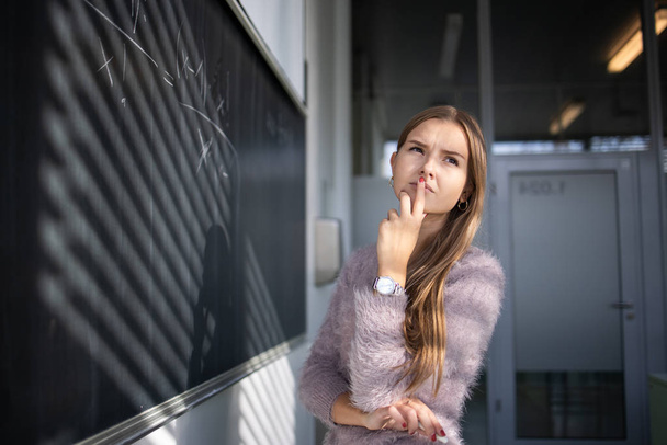 Pretty, young female student in front of a blackboard  - Foto, afbeelding