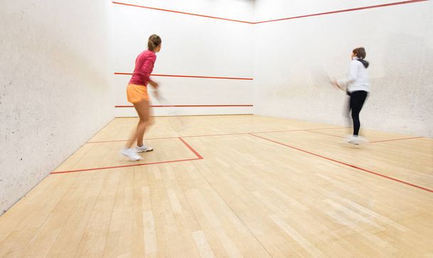 Two female squash players in action on a squash court  - Valokuva, kuva