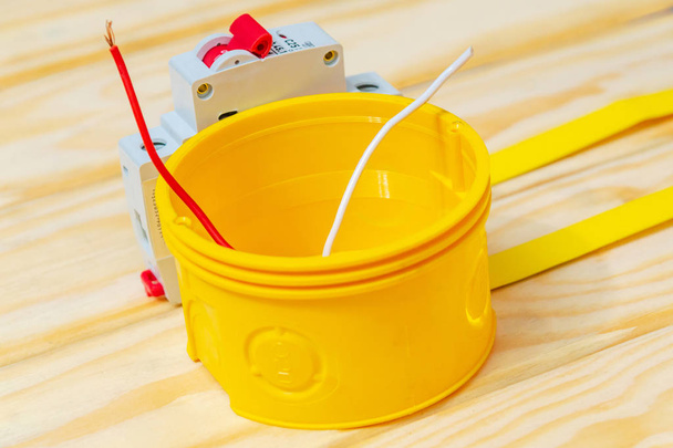 Caja amarilla de unión eléctrica con cable utilizado en el proceso de instalación eléctrica
 - Foto, Imagen