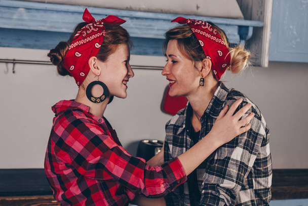 Family, friendship and people concept - happy mother with little daughter. With red lips in a bandana have fun in the home kitchen. Pin-up style photo. - Photo, image