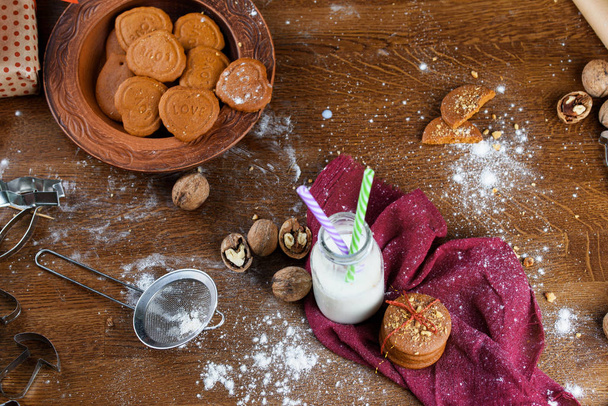 Un verre de lait avec biscuits de Noël, noix, cadeaux sur la table
. - Photo, image
