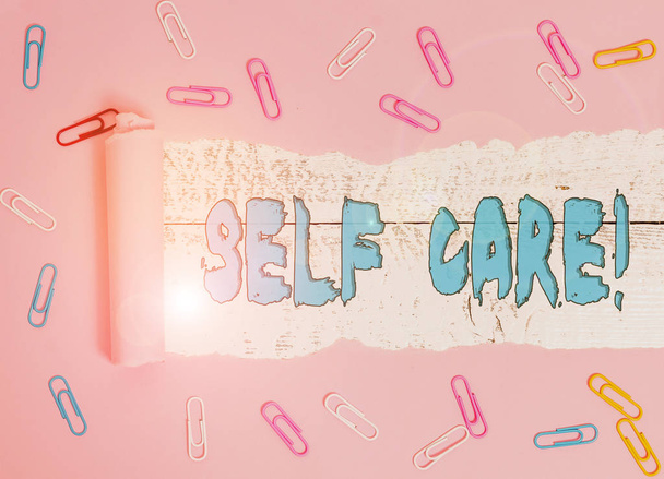 Conceptual hand writing showing Self Care. Business photo showcasing practice of taking action to preserve or improve ones own health Paper clip and torn cardboard on wood classic table backdrop. - Photo, Image