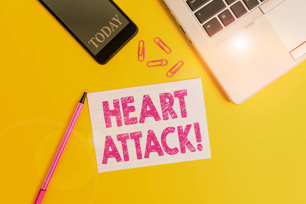 Word writing text Heart Attack. Business concept for sudden occurrence of coronary thrombosis resulting in death Trendy open laptop smartphone marker paper sheet clips colored background. - 写真・画像