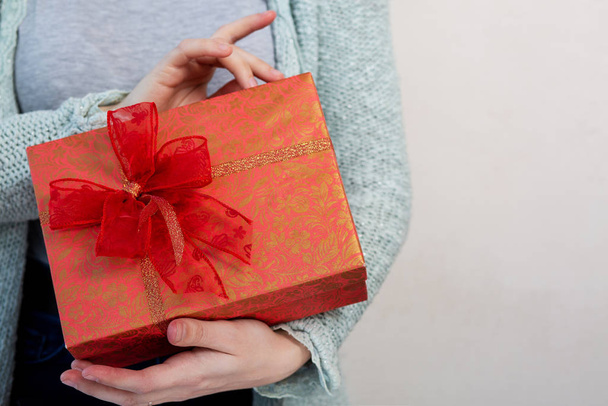 Женские руки держат подарочную коробку на сером фоне
 - Фото, изображение