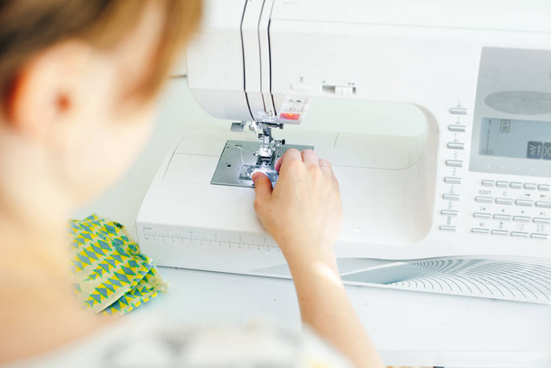 Las manos femeninas que cosen la tela blanca en la máquina de fabricación profesional en el lugar de trabajo
 - Foto, Imagen