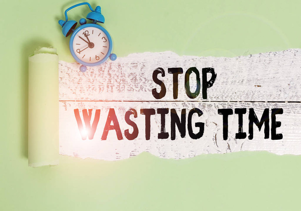 Writing note showing Stop Wasting Time. Business photo showcasing advising demonstrating or group start planning and use it wisely Alarm clock and torn cardboard on a wooden classic table backdrop. - Photo, Image