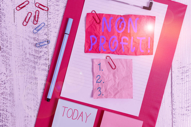 Text sign showing Non Profit. Conceptual photo not making or conducted primarily to make profit organization Clipboard sheet crushed sticky note clip notepads marker wooden background. - Photo, Image