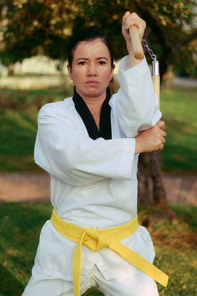 kolumbianische, lateinamerikanische Frau übt Taekwondo mit Nunchakus linken Angriff - Foto, Bild