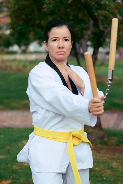 Colombiana, mujer latinoamericana practicando taekwondo con nunchakus móvil, mano derecha
 - Foto, Imagen