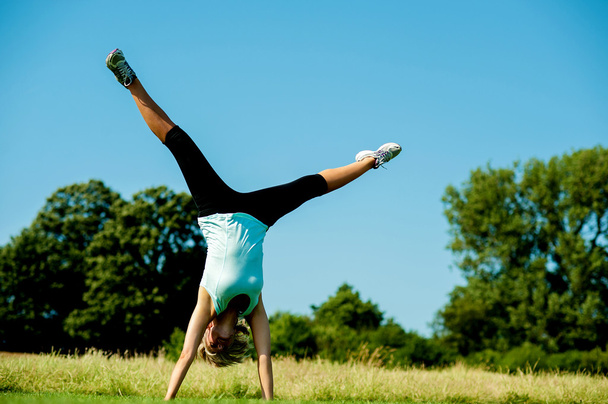 Woman doing cartwheel in a field - Photo, image