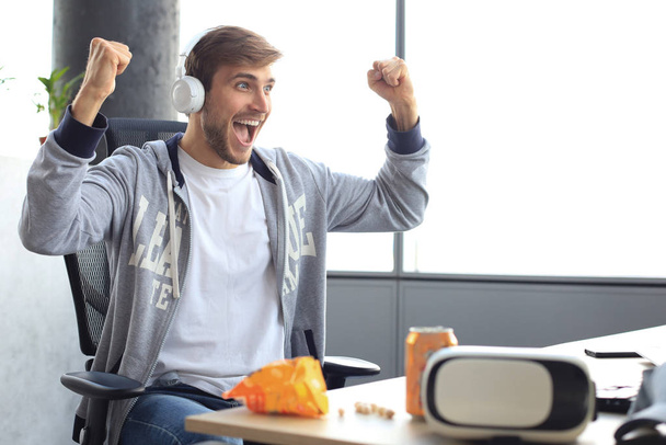 Portrait of ecstatic gamer guy in headphones screaming and rejoicing while playing video games on computer. - Photo, image