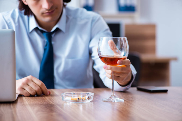 Male employee drinking alcohol and smoking cigarettes at workpla - Foto, Imagem