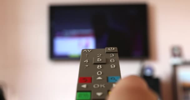 Férfi kéz fogja a TV távirányítását az okos TV-nek, Csatorna szörfözés a homályos Internet TV-n a háttérben. Close Up View - Dci 4k Videó - Felvétel, videó