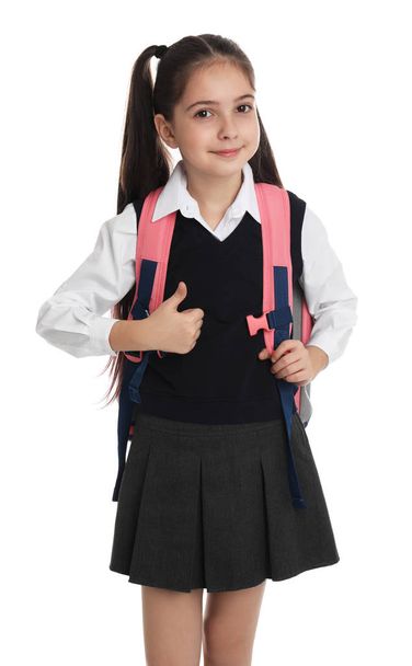 Little girl in school uniform with backpack on white background - Foto, afbeelding