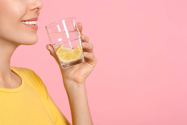 Young woman drinking tasty lemon water on pink background, close - Photo, image