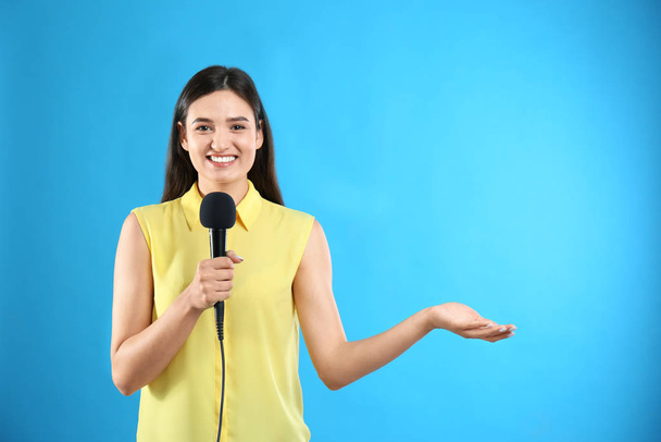 Young female journalist with microphone on blue background - Foto, immagini