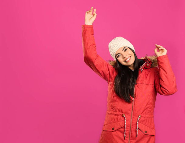 Boldog fiatal nő meleg ruhában rózsaszín háttérrel, hely a szövegnek. Téli vakáció - Fotó, kép