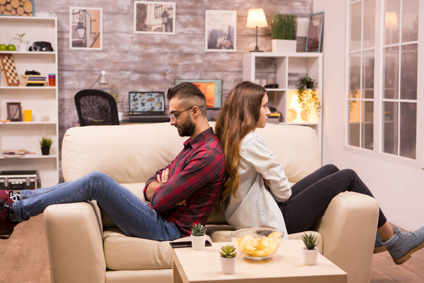 Couple sitting back to back on the couch ignoring each other - Foto, afbeelding