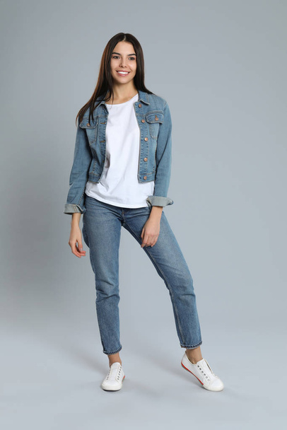 Young woman in stylish jeans on grey background - Zdjęcie, obraz
