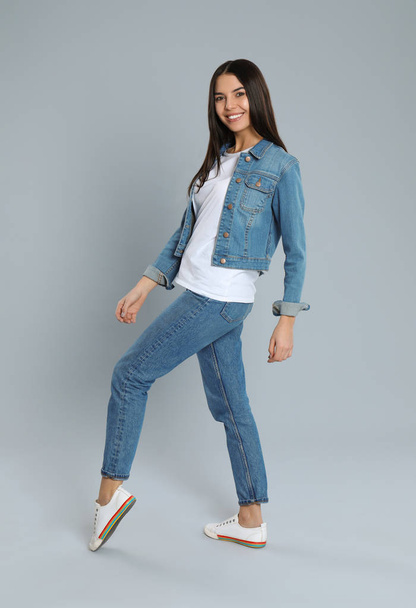 Young woman in stylish jeans on grey background - Foto, afbeelding