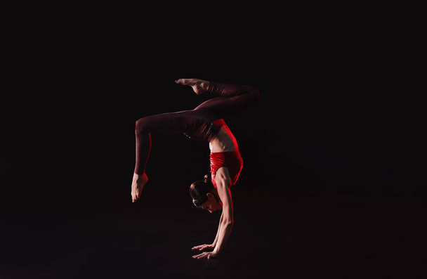 Giovane donna che esegue elemento acrobatico sul palco al chiuso
 - Foto, immagini