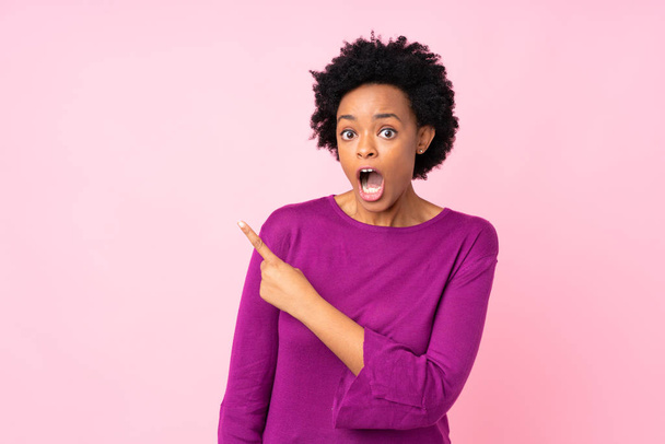 African american woman over isolated pink background surprised and pointing side - Photo, Image
