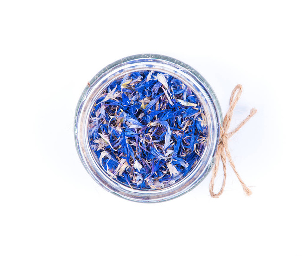 Blue cornflower centaurea dried petals in a glass jar isolated on white background. - Photo, Image