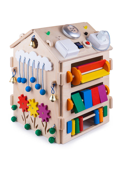 Wooden  busy board house - educational toy for children, babies on a white isolated background, consisting of multi-colored wooden flower puzzle pieces, bells, gear, sorter, switches, lamp - Photo, Image