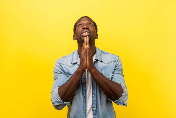Portrait of young religious man holding hands in prayer looking  - Photo, image