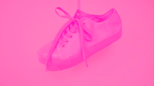 Par de zapatillas de deporte femeninas rosadas que cuelgan sobre fondo rosa. Bright Rose Womans Entrenadores cuelgan de la cuerda. Estímulo funky
 - Metraje, vídeo